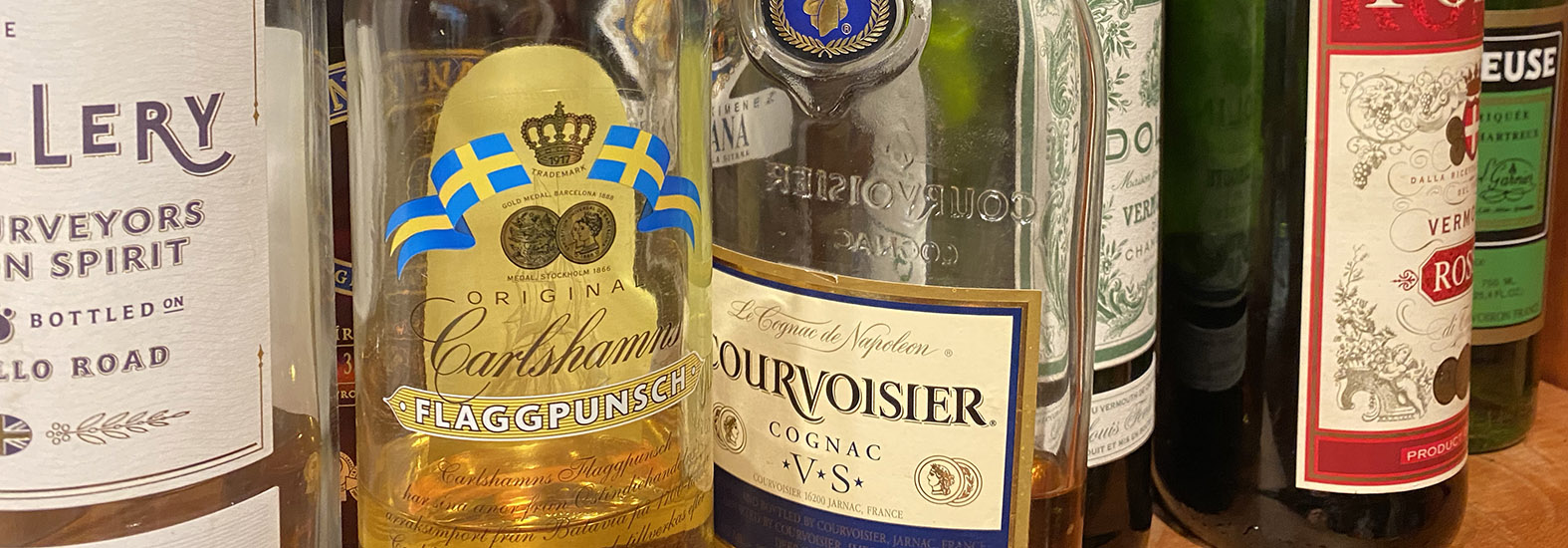 A shelf of a home bar, crowded with various bottles of liquor.